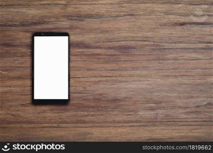 Mobile smartphone with blank screen on wood desk background with copy space. Top down