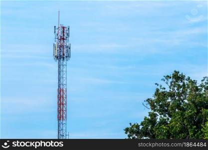 Mobile station receiver antenna tower with fluffy clouds blue sky daylight background.