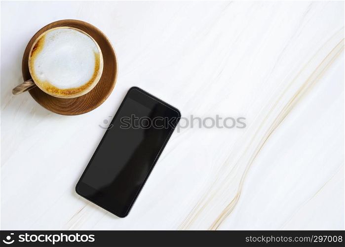Mobile with empty screen with latte coffee cup on white marble table with free copy space. Business and technology.