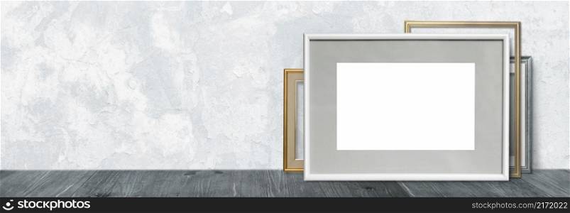 Mock-up of a white frame on a wooden shelf or table against a wall background