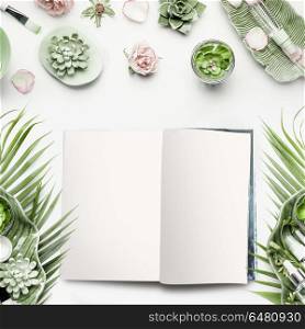 Mock-up of open magazine or catalog for beauty and cosmetic products. Modern natural skin care equipment with roses, succulents, facial mist water spray and green tropical leaves on white background