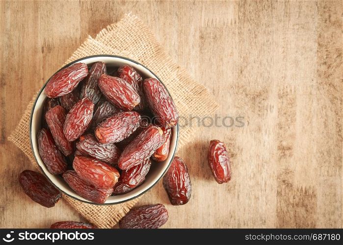 mock up picture of dates palm fruit in cup on wooden table background. Dates palm fruit dry is snack healthy.