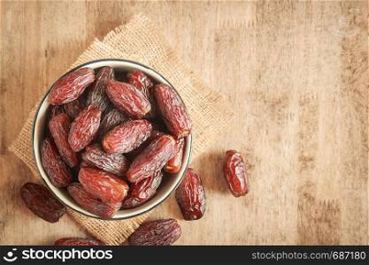 mock up picture of dates palm fruit in cup on wooden table background. Dates palm fruit dry is snack healthy.