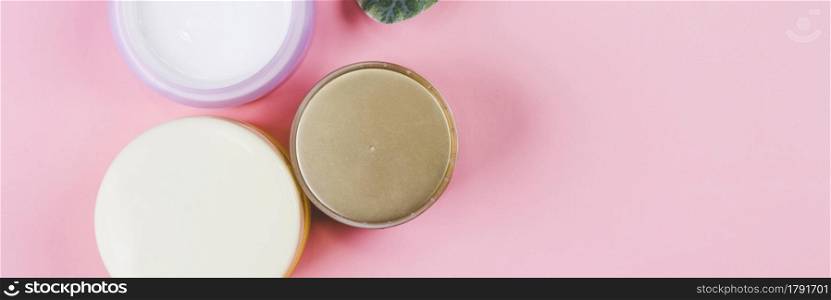 Mockup cosmetic jar with cream or lotion and leaf isolated on pink background, mock up package for advertising, skincare or cosmetology, top view, flat lay, skin care and treatment with product.