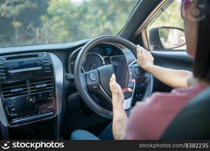 Mockup ima≥of a woman holding and using mobi≤pho≠with blank screen whi≤driver a car, for GPS, Lifesty≤s photo in car, Interior, front view. With woman hand holding pho≠.