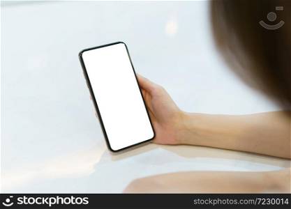 Mockup image of hand holding mobile phone with blank white screen.