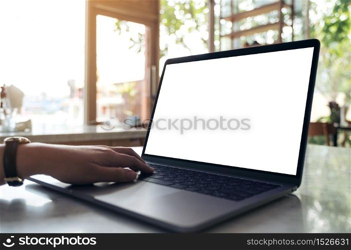 Mockup image of hands using and typing on laptop with blank white desktop screen on table in modern cafe