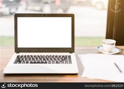 Mockup image of laptop with blank white screen,smart phone and document on wooden table of In the coffee shop.
