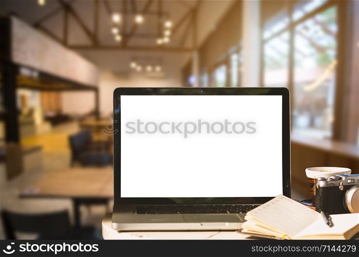 Mockup image of laptop with blank white screen with camera,notebook,coffee cup on wooden table of In the coffee shop background.