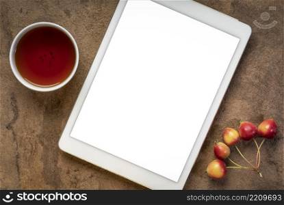 mockup of digital tablet with a blank isolated screen  clipping path included , flat lay with a cup of tea and crab apples on a handmade textured paper