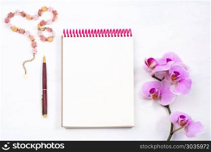 Mockup with notepad, pen and pink orchid, top view. Female workspace mockup with notepad, pen and pink orchid on white background, top view