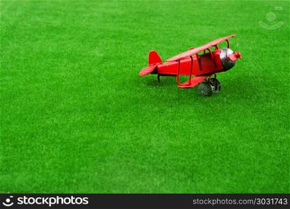 Model airplane in grass. Red little retro model airplane in green grass