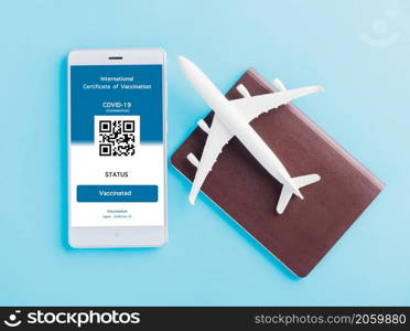 Model airplane, passport and immunity pass are arranged application on smartphone on blue background, Travel concept during Covid-19 pandemic digital International Vaccination Certification concept