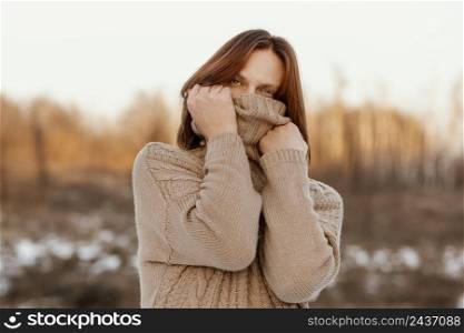 model covering face with beige sweater