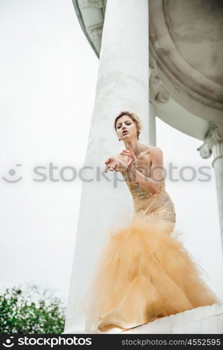 model girl dress gold angel posing in the woods near the old columns