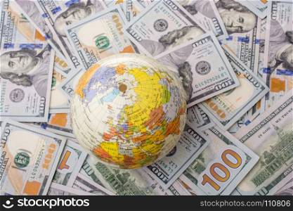 Model globe is placed on spread US dollar banknotes