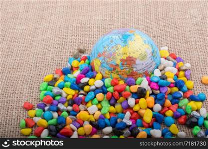 Model globe placed amid colorful pebbles