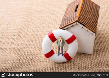 Model house and a life preserver with a man figure on it