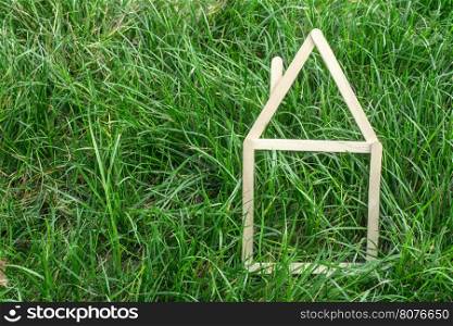 Model house made of wooden sticks on green grass