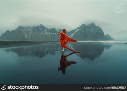 Model in elegant gown on Reynisfjara beach scenic photography. Picture of person with mountains on background. High quality wallpaper. Photo concept for ads, travel blog, magazine, article. Model in elegant gown on Reynisfjara beach scenic photography