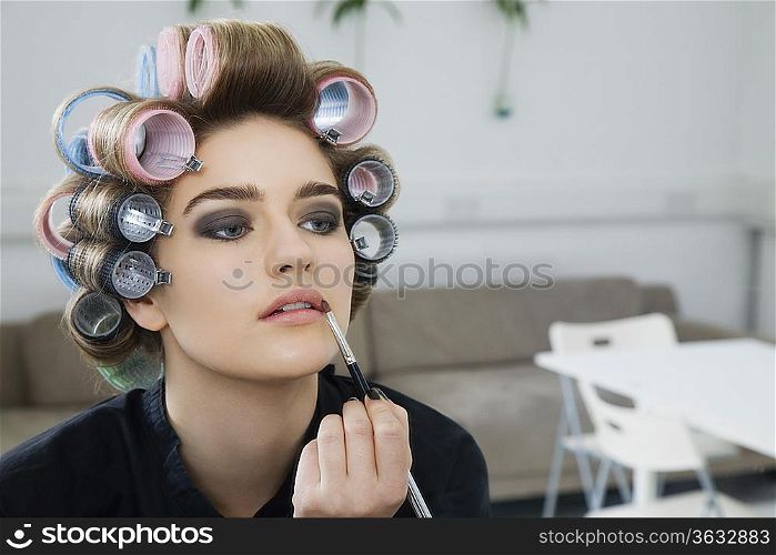 Model in Hair Curlers Applying Lip Gloss