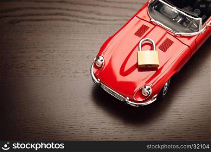 Model of a red car with padlock on wooden surface, view from above. Concept of security. Close up, copy space.