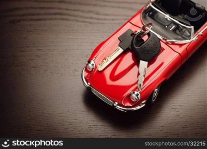Model of a red car with padlock on wooden surface, view from above. Concept of buying or selling a car. Close up, copy space.