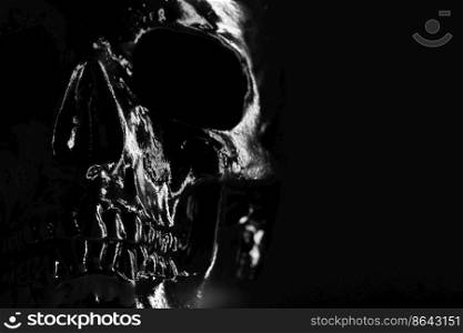 Model of human skull painted with black on dark background with illumination. Concept of fear and horror, Halloween celebration. Copy space.. Model of human skull painted with black on dark background with illumination. Concept of fear and horror, Halloween celebration. Copy space