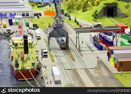 model of railroad station and sea port. ship, railroad, train, buildings and other constructions. focus on a train.