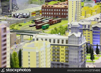 model of railroad station. railroad, trains, buildings and other constructions. focus on three floors building in top of image.