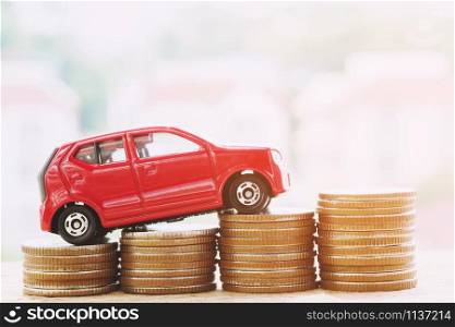 model of toy car red on over a lot money of stacked coins - insurance, loan and buying car finance concept. isolated white background.