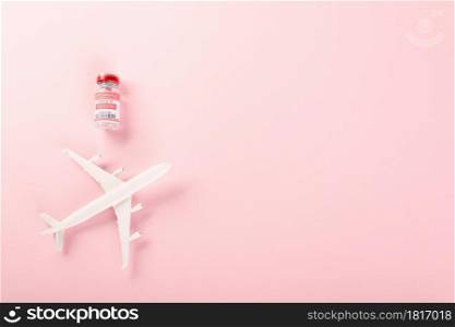 Model plane and COVID-19 coronavirus vaccine vials bottles for vaccination, buy vaccine, tourism worldwide delivery studio shot isolated pink background with copy space for text