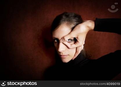Model wearing dark makeup with hand in front of her eye