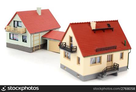 Models of two houses with garage for car on white background. Focus on the distant house.