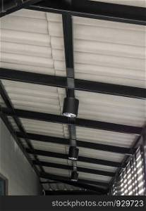 Moden black electrical lamp,hanging on the metal beam of the urban house.
