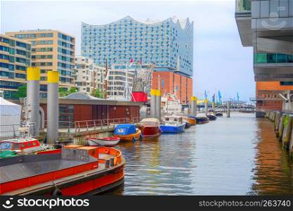 Modern architecture of Hamburg Hafen harbor district in downtwon, embankment with moored boats, opera house building and industrial city port on the background, Germany