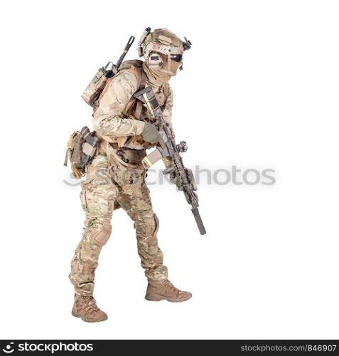 Modern army infantry rifleman in camo uniform, radio headset on helmet, ammo on load carrier, sneaking, crouching, aiming and shooting with service rifle studio shoot isolated on white background. Army soldier crouching with rifle studio shoot