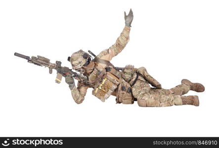 Modern army soldier, infantry rifleman equipped with tactical ammunition and radio, lying on ground, observing territory trough optical sight, aiming, shooting with assault rifle isolated studio shoot. Soldier shooting from ground isolated studio shoot