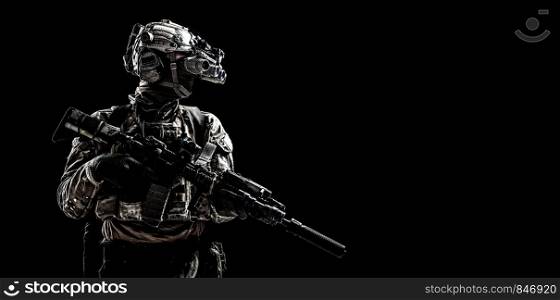Modern army special forces equipped soldier, anti terrorist squad fighter, elite mercenary armed assault rifle, standing in darkness with night vision goggles on helmet, studio portrait, copyspace. Army special forces shooter low key studio shoot