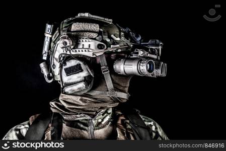 Modern army special forces soldier, anti terrorist squad fighter, elite commando warrior wearing mask, using four lenses night vision goggles in low light conditions, studio shoot on black background. Soldier in night view goggles low key studio shoot