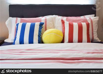 Modern bedroom interior with blue,yellow and red striped pillows on bed
