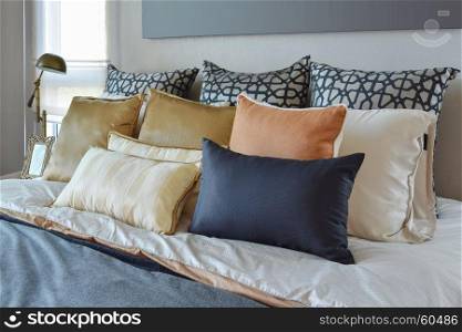 modern bedroom interior with orange and gold pillows on bed and bedside table lamp