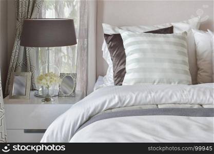 modern bedroom interior with striped pillow on bed and bedside table lamp at home