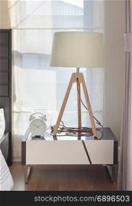 modern bedroom interior with wooden lamp and alarm clock on bedside table