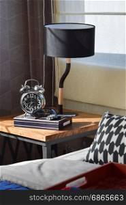 modern bedroom with black lamp and alarm clock on wooden table at home