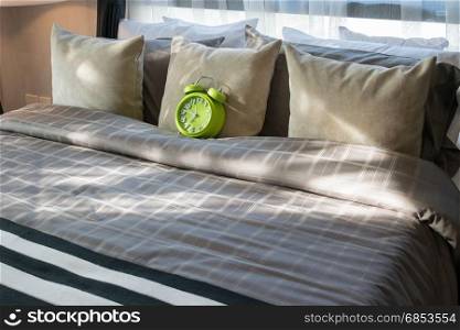 modern bedroom with green alarm clock and pillows on bed