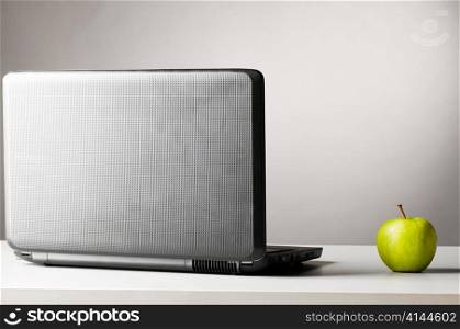 modern black laptop on table with green fresh apple