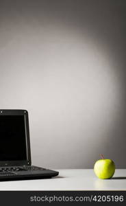 modern black laptop on table with green fresh apple