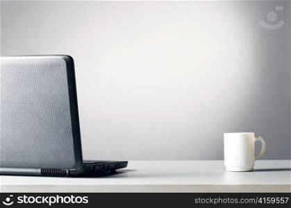 modern black laptop with white cup of coffee, blue toned