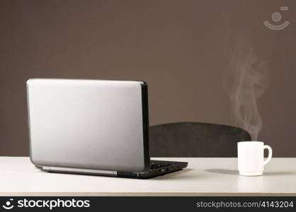 modern black laptop with white cup of coffee with steam